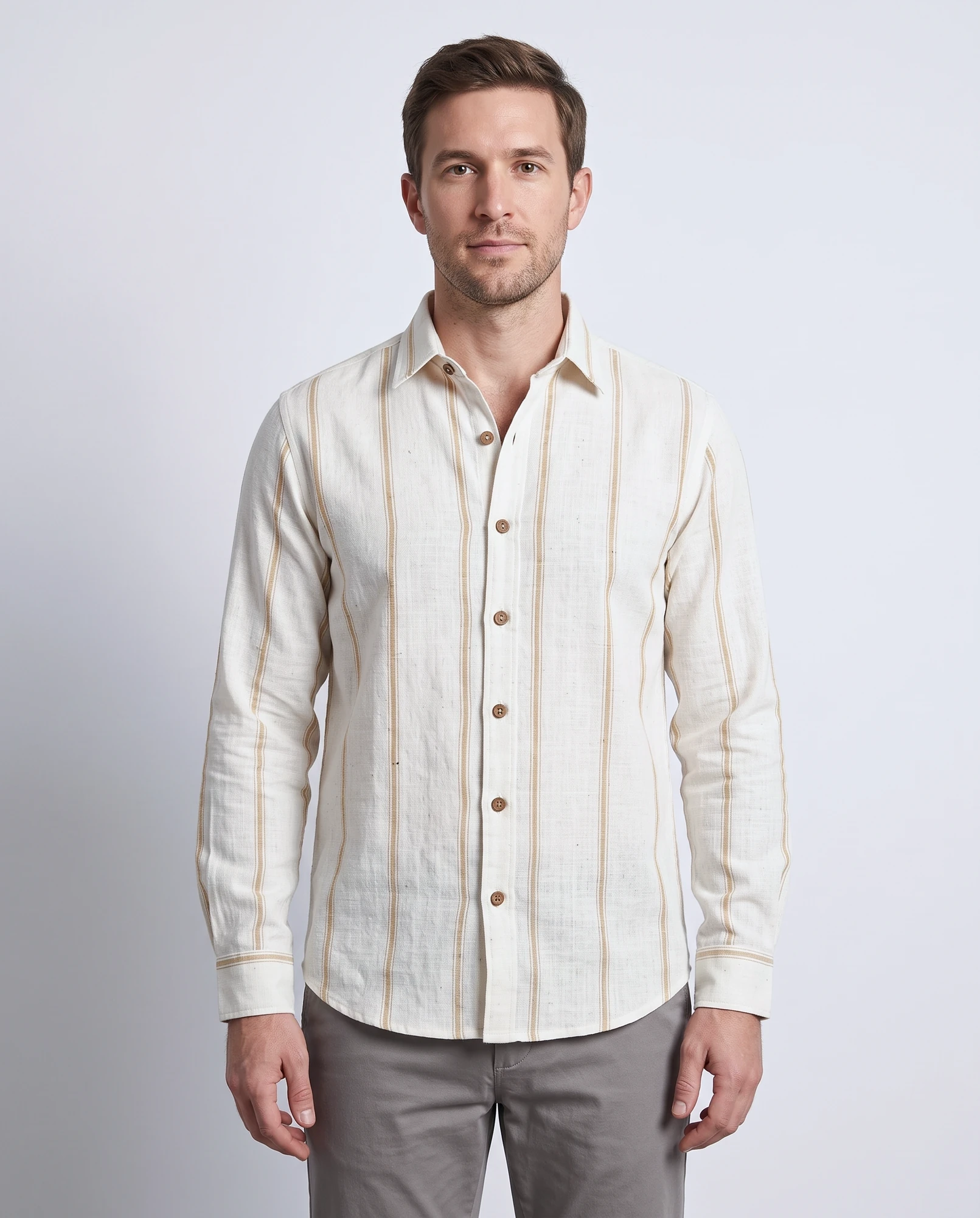 Wheat Loom khadi striped shirt worn untucked, front view showing the widely spaced gold lines, point collar and coconut-shell buttons