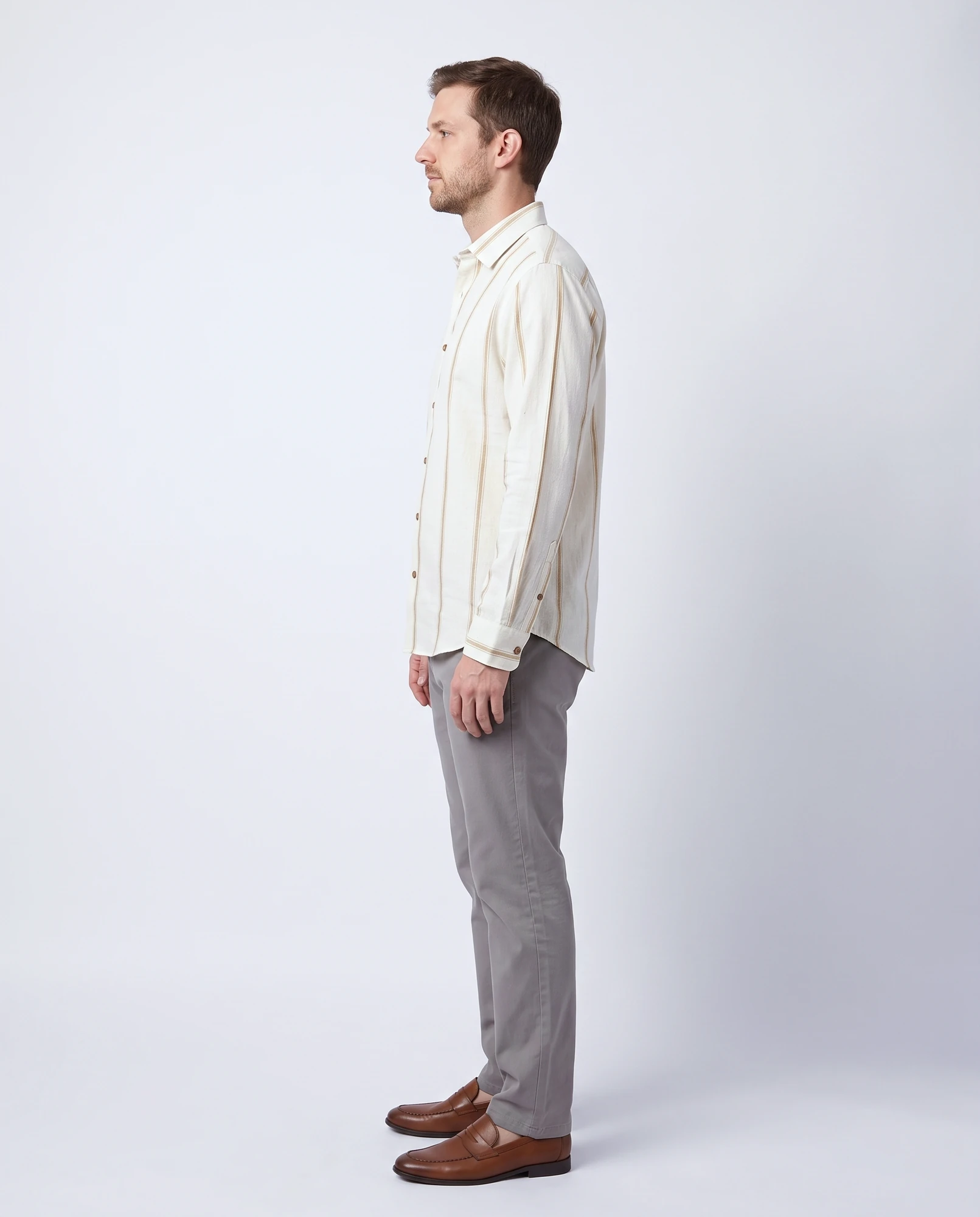 Left side view of a man wearing a handwoven natural khadi shirt with gold stripes, showing the sleeve, barrel cuff and curved hem