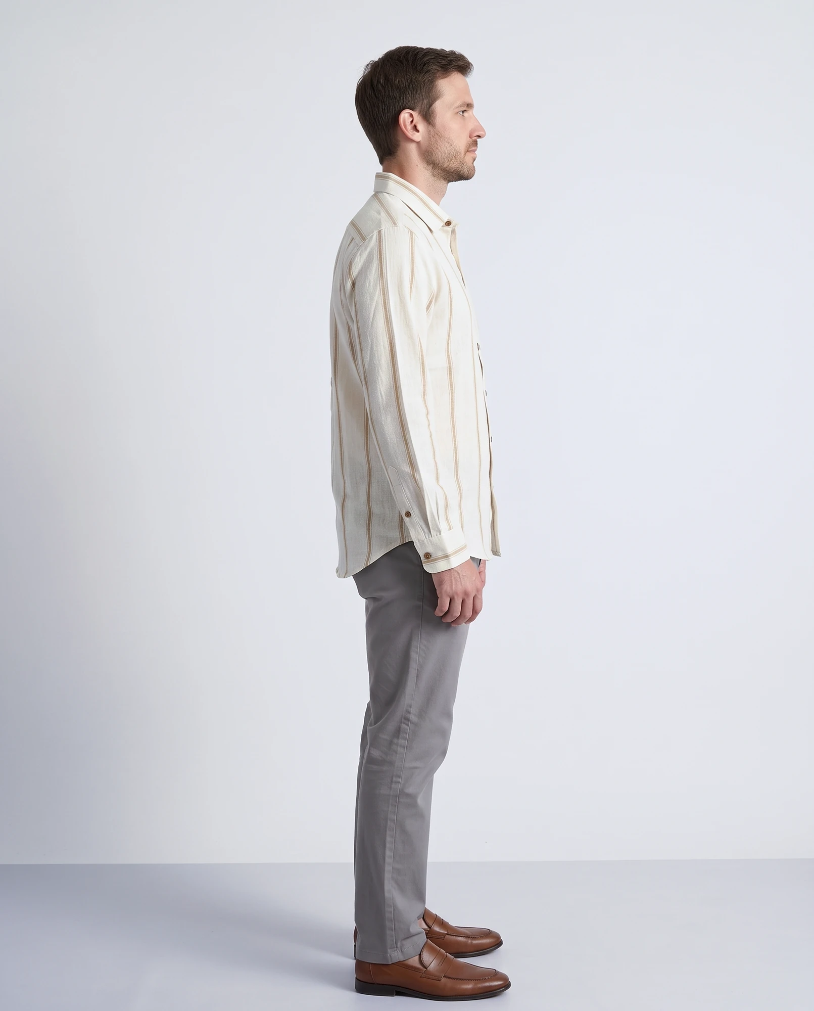 Right side view of a man wearing a handwoven natural khadi shirt with gold stripes, showing the sleeve, barrel cuff and curved hem